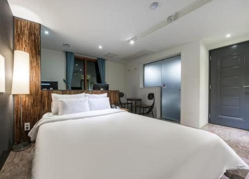 釜山Hotel Days A的一张大白色的床,位于一个有门的房间
