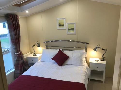 a bedroom with a bed with two lamps on two tables at Hot Tub Accommodation North Wales Caravan in Rhyl