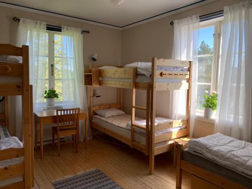 a room with bunk beds and a table and a desk at Vandrarhemmet Gammelgården in Bengtsfors