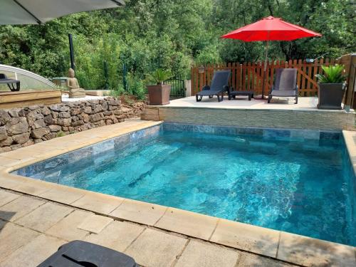 - une piscine avec un parasol, deux chaises et une table dans l'établissement Natur'ânes, à Mialet