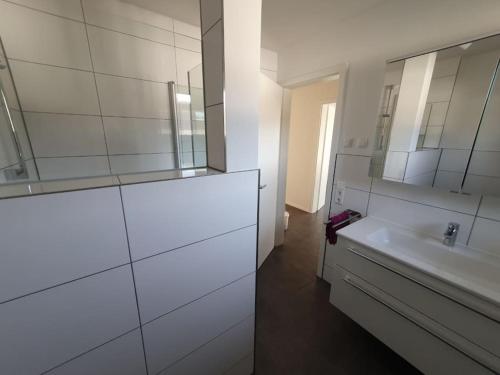 a white bathroom with a sink and a mirror at Edle Ferienwohnung in Neubau in Riedlingen