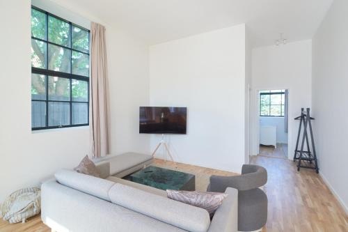 a white living room with a couch and a tv at Cozy and Bright Apartments with Private Car Park in Copenhagen