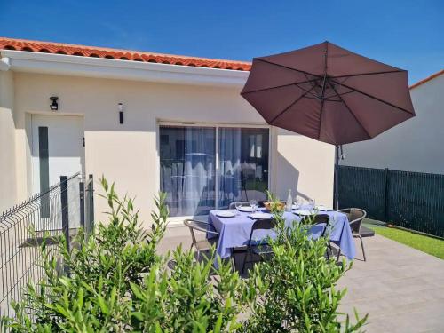 een patio met een tafel en een parasol bij Le Brasil - Maison 74 m - Calme avec terrasse Sud classée 3 étoiles in Le Boulou