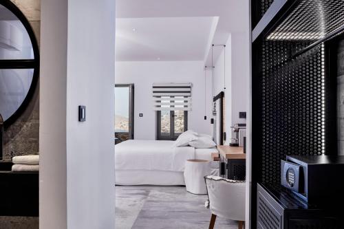 a bedroom with a white bed and a table and chairs at Liostasi in Ios Chora