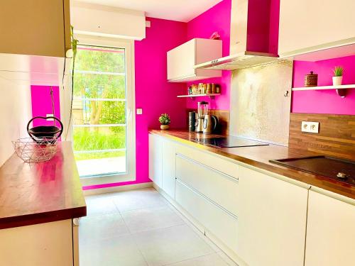 uma cozinha com paredes cor-de-rosa e um balcão em Grand et charmant appartement familial, 3 chambres, et moderne avec grand jardin et parking privatif aux portes de Paris em La Garenne-Colombes
