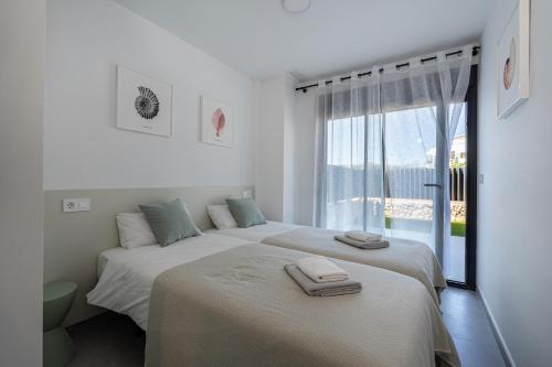 2 Betten in einem weißen Zimmer mit Fenster in der Unterkunft Rennes Arenal Playa 3 in Jávea