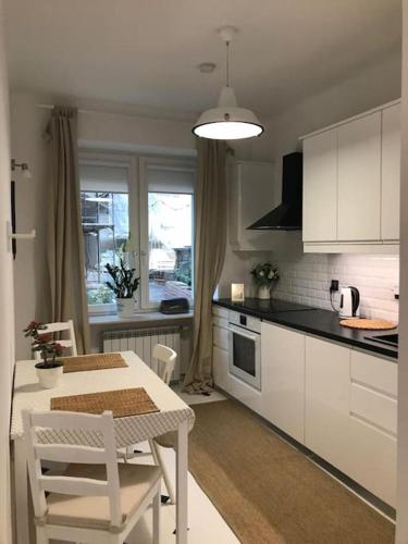 a kitchen with white cabinets and a table and chairs at Piękne, nowoczesne mieszkanie na ulicy Chmielnej, samo centrum. in Warsaw