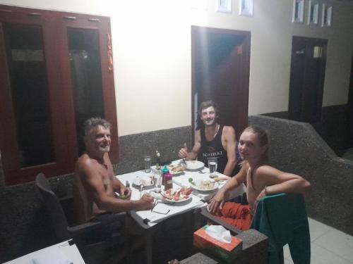 a group of people sitting at a table eating food at Mango Homestay in Sekotong
