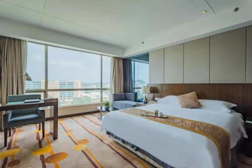 una camera d'albergo con letto, scrivania e finestra di Santavan Hotel Shenzhen Guangming a Bao'an