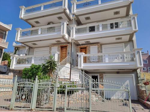 a white building with balconies and a fence at Ηome Rent Chalkida in Kánithos