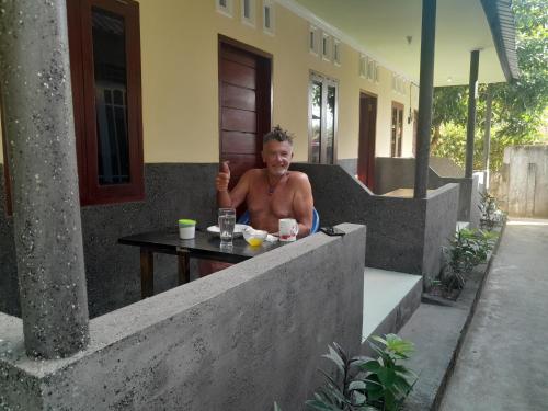 a man sitting at a table giving a thumbs up at Mango Homestay in Sekotong
