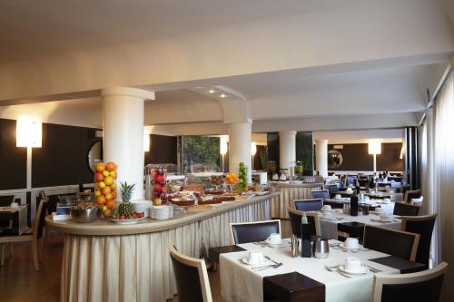 un restaurant avec des tables et des chaises blanches et un bar dans l'établissement Albergo Celide, à Lucques