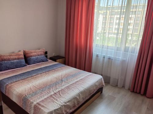 a bedroom with a bed with red curtains and a window at Двустаен апартамент в Смирненски. До селената in Plovdiv