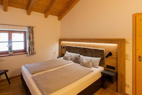 a bedroom with a large bed with a wooden headboard at Schleipfnerhof Urlaub auf dem Bauernhof in Bernau am Chiemsee