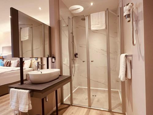 a bathroom with a glass shower and a sink at MEA HOTEL TRIER in Trier