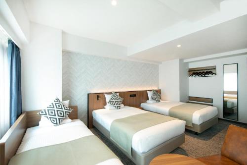 une chambre d'hôtel avec deux lits et une chaise dans l'établissement HOTEL MYSTAYS Kumamoto Riverside, à Kumamoto