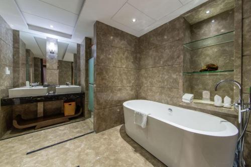 a bathroom with a bath tub and a sink at Santavan Hotel Shenzhen Guangming in Bao'an