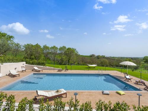 una gran piscina con sillas y sombrilla en Inviting Holiday Home in San Costanzo with Swimming Pool, en San Costanzo