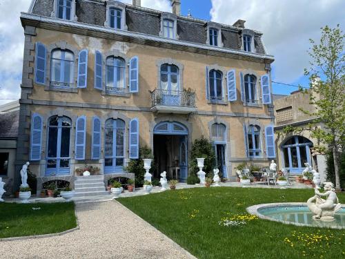 une grande maison avec des volets bleus et une fontaine dans l'établissement Maison d'Hercule, à Mayenne