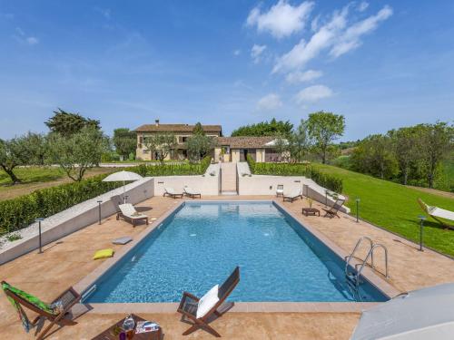 una piscina con sillas y una casa en Inviting Holiday Home in San Costanzo with Swimming Pool, en San Costanzo