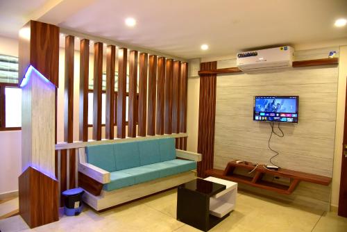 ROYAL CASTLE HOTEL في مانانثافادي: غرفة معيشة مع مقعد أزرق وتلفزيون