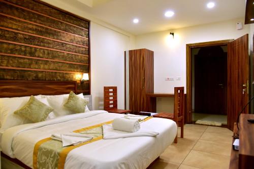 ein Schlafzimmer mit einem großen weißen Bett mit Handtüchern darauf in der Unterkunft ROYAL CASTLE HOTEL in Mananthavady