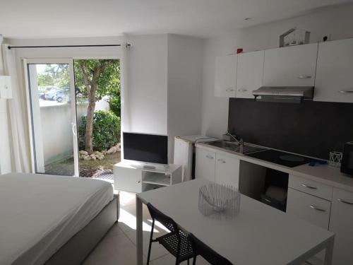 Cette chambre blanche dispose d'un lit, d'une table et d'une cuisine. dans l'établissement Belle Maisonnette avec jardin 2 pas du VIEUX PORT, à La Rochelle