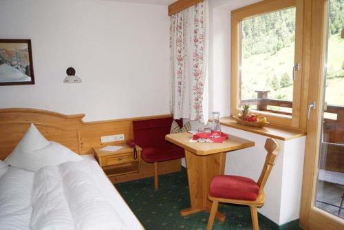 a bedroom with a bed and a desk and a window at Apartpension Schollberg in Sankt Anton am Arlberg