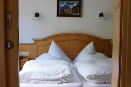 1 dormitorio con 1 cama con sábanas y almohadas blancas en Apartpension Schollberg en Sankt Anton am Arlberg