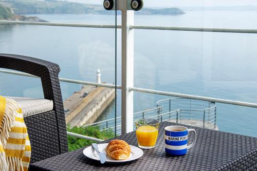 a table with a plate of croissants and a cup of orange juice at Marine Point, Mevagissey - sensational cliff top views of harbour and bay in Mevagissey