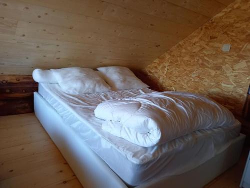ein unmarkiertes Bett in einem Zimmer mit Holzdecke in der Unterkunft Les Petites Fustes Dans La Prairie in Coucouron