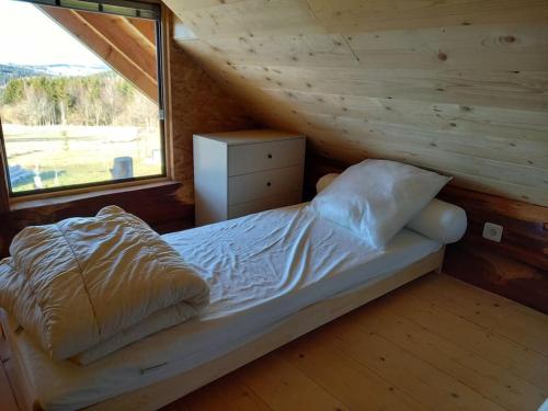Bett in einem Holzzimmer mit Fenster in der Unterkunft Les Petites Fustes Dans La Prairie in Coucouron