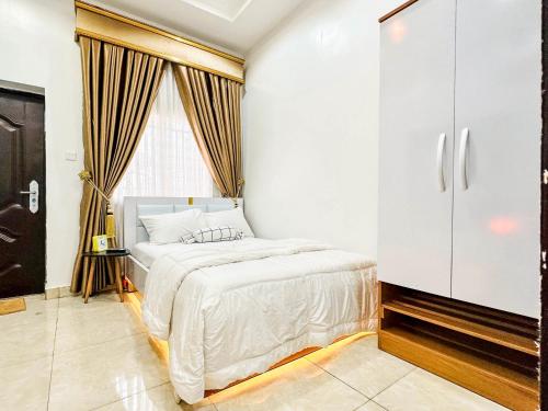 um quarto com uma cama branca e um armário em Cozy Apartment - Hideaway with 5G WiFi em Abuja