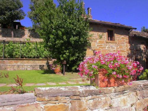 un mur en pierre avec des fleurs devant un bâtiment dans l'établissement Spacious Cottage in Cortona with Swimming Pool, à Cortone