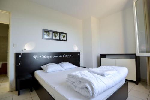 a bedroom with a black and white bed with white sheets at La Résidence du Château de Jouarres in Azille