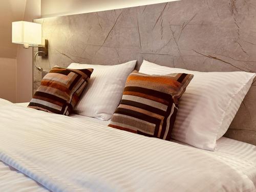 Una cama con almohadas blancas y almohadas a rayas. en MEA HOTEL TRIER en Tréveris