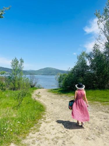 a woman in a pink dress walking down a dirt road at Apartamenty Paszkówka in Pietrzykowice