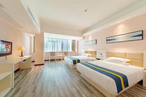 a hotel room with two beds and a flat screen tv at Unitour Hotel, Nanning Dongge Traditional Chinese Medicine No 1 Affiliated in Nanning