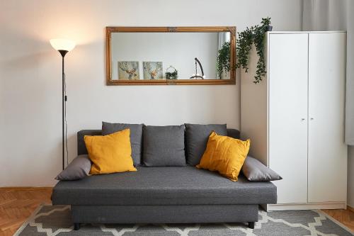 Apartments on Miodowa في كراكوف: أريكة رمادية مع وسائد صفراء في غرفة المعيشة