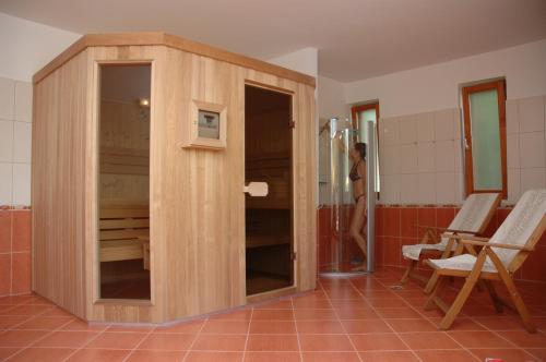 a wooden cabinet in a bathroom with a person in the shower at Hullám Villa B&B in Balatonmáriafürdő