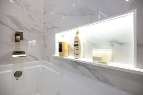 Baño blanco con lavabo y espejo en Lakefront Retreat: Designer Suite w/Stunning Views, en Toronto