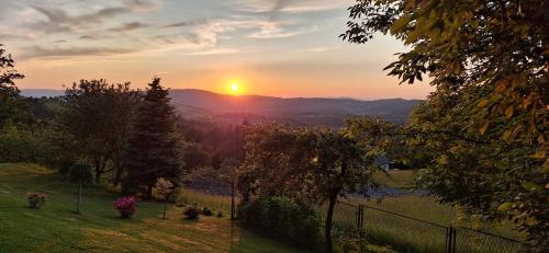 a sunset in a field with the sun in the distance at Agroturystyka Koronkowe Zacisze in Koniaków