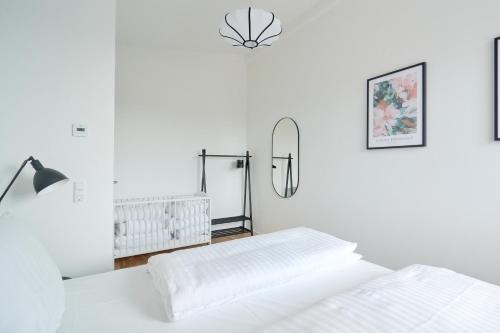 a white bedroom with two beds and a lamp at Cozy and Bright Apartments with Private Car Park in Copenhagen