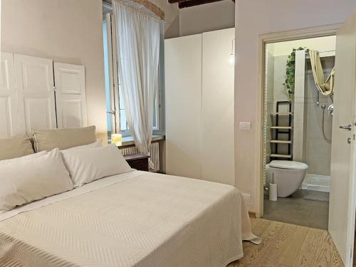 1 dormitorio con 1 cama blanca grande y baño en Suite 9, Parma Centro en Parma