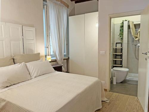 Un dormitorio con una gran cama blanca y un baño. en Suite 9, Parma Centro, en Parma