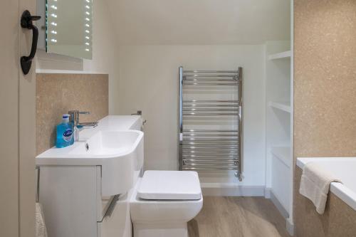 a white bathroom with a toilet and a sink at Dorset Holiday Barns in Sherborne
