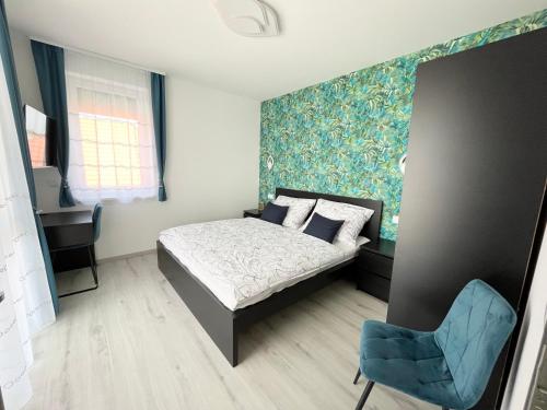 a bedroom with a bed and a blue chair at Napfény Terasz Apartman in Vonyarcvashegy