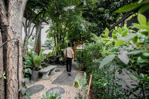 a man walking down a path in a park at Ying Yang House Sawankhalok in Sawankhalok