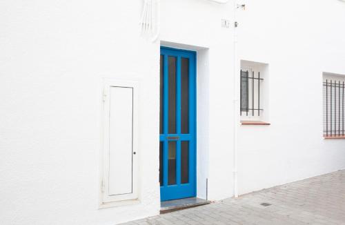 una puerta azul en el lateral de un edificio blanco en Ca l'Estrella II L'Estartit, en L'Estartit