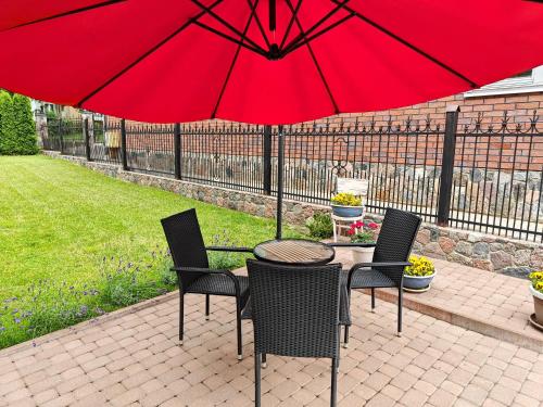 einen Tisch und Stühle mit einem roten Regenschirm auf einer Terrasse in der Unterkunft Vakaro Namai in Alytus